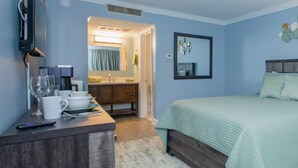A bedroom with a bed, a dresser, a mirror, and a wall-mounted artwork.