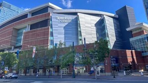 A modern building with a 'Spectrum Center' sign, featuring a curved facade, large windows, and a mix of brick and glass materials.