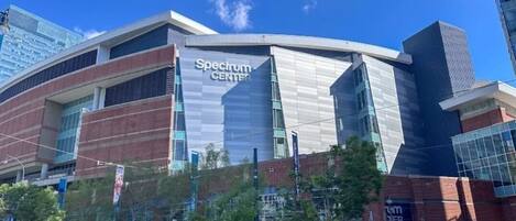 A modern building with a 'Spectrum Center' sign, featuring a curved facade, large windows, and a mix of brick and glass materials.