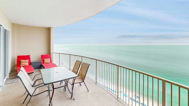 Ein Balkon mit Tisch und Stühlen, einem Geländer und Blick auf das Meer.