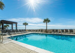 A clear blue pool with lounge chairs and palm trees, surrounded by a pergola. - Gulf Front with sweeping views from 20th floor (Panama City Beach)