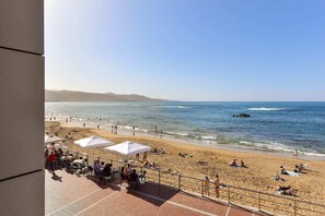 Una spiaggia con persone, ombrelloni e vista sull'oceano.