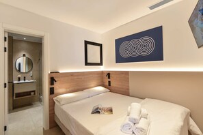 Una camera d'albergo con un letto, un comodino, uno specchio e un'opera d'arte appesa al muro.