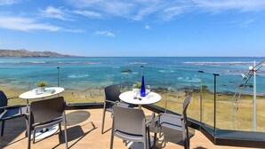 An outdoor seating area with a clear view of the sea, tables with chairs, and a glass balustrade. - 1 bedroom interior apartment (Las Palmas de Gran Canaria)