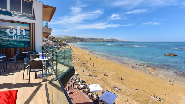 A seaside hotel with a balcony overlooking a beach, a sign reading 'oh SUITES', and clear blue skies. - 1 bedroom interior apartment (Las Palmas de Gran Canaria)