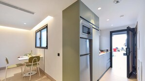 A modern kitchen with a built-in oven and microwave, a dining area with a table and chairs, and a view of the outside through a door. - 1 bedroom penthouse apartment (Las Palmas de Gran Canaria)