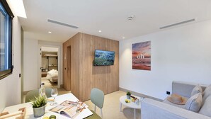 A modern hotel room with a dining area, a TV mounted on the wall, a poster, and a sofa. - 1 bedroom penthouse apartment (Las Palmas de Gran Canaria)