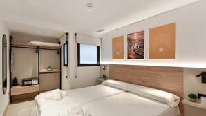 A modern hotel room with a large bed, a walk-in closet, a small desk, and artwork on the walls. - 1 bedroom penthouse apartment (Las Palmas de Gran Canaria)