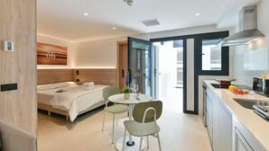 A modern hotel room with a bed, a dining table with chairs, a kitchen area, and a sliding glass door leading to an outdoor area. - Top Floor Penthouse Studio (Las Palmas de Gran Canaria)