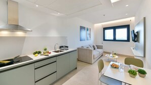 A modern kitchen with a stove, sink, and a dining area with a table and chairs. - Sea view family studio first floor (Las Palmas de Gran Canaria)