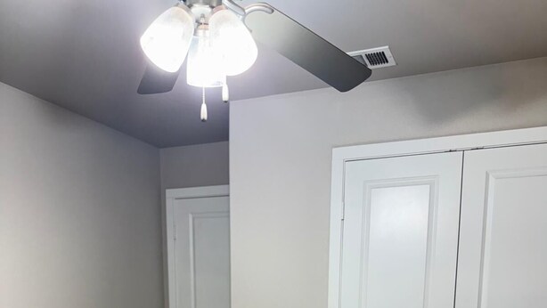 Ein Schlafzimmer mit einem Bett, einem Deckenventilator und weißen Doppeltüren.