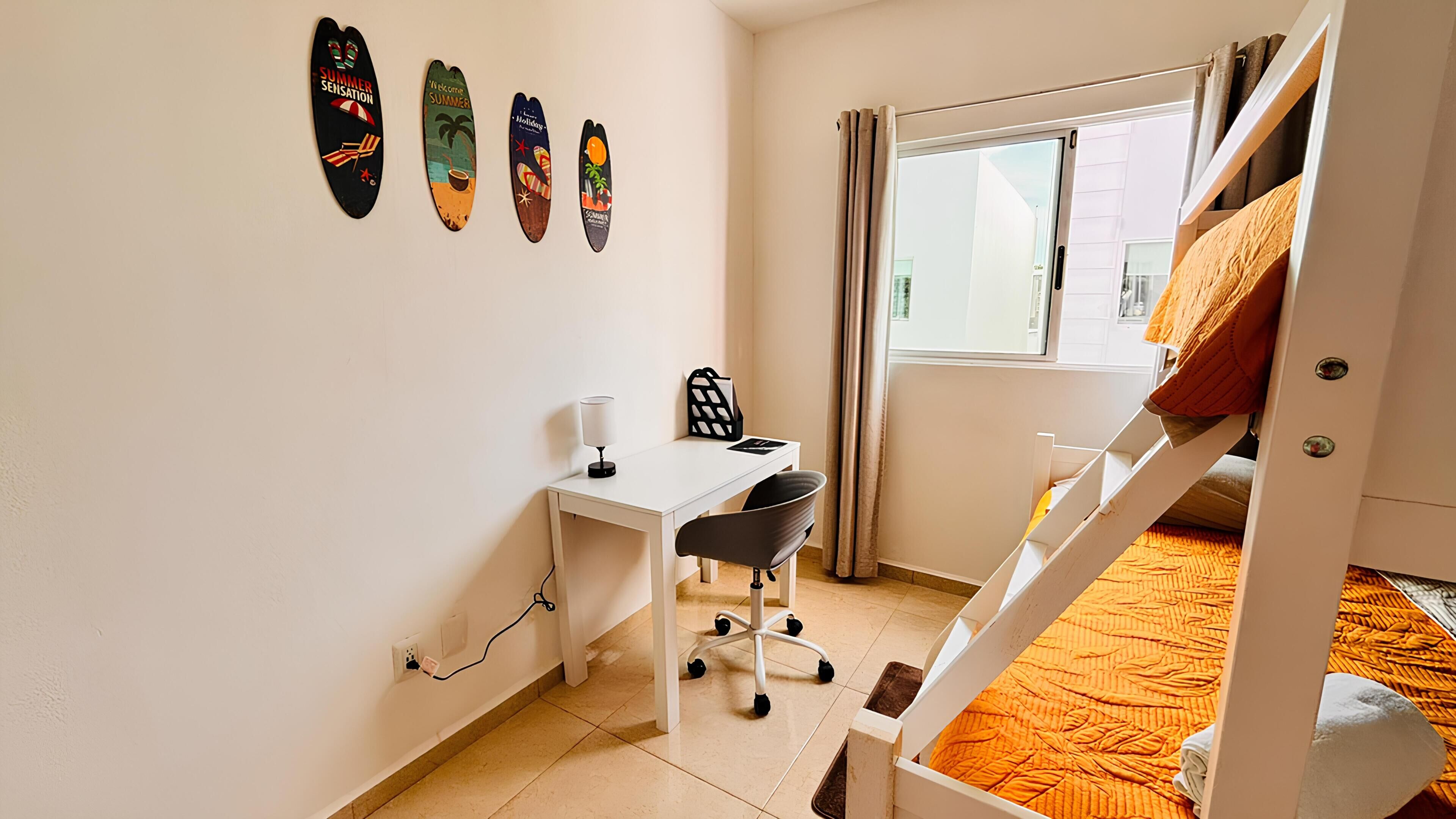 Une chambre avec un lit superposé, un bureau avec une chaise, une fenêtre avec des rideaux et des éléments de décoration murale.