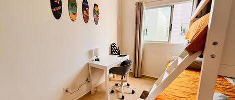 Une chambre avec un lit superposé, un bureau avec une chaise, une fenêtre avec des rideaux et des éléments de décoration murale.