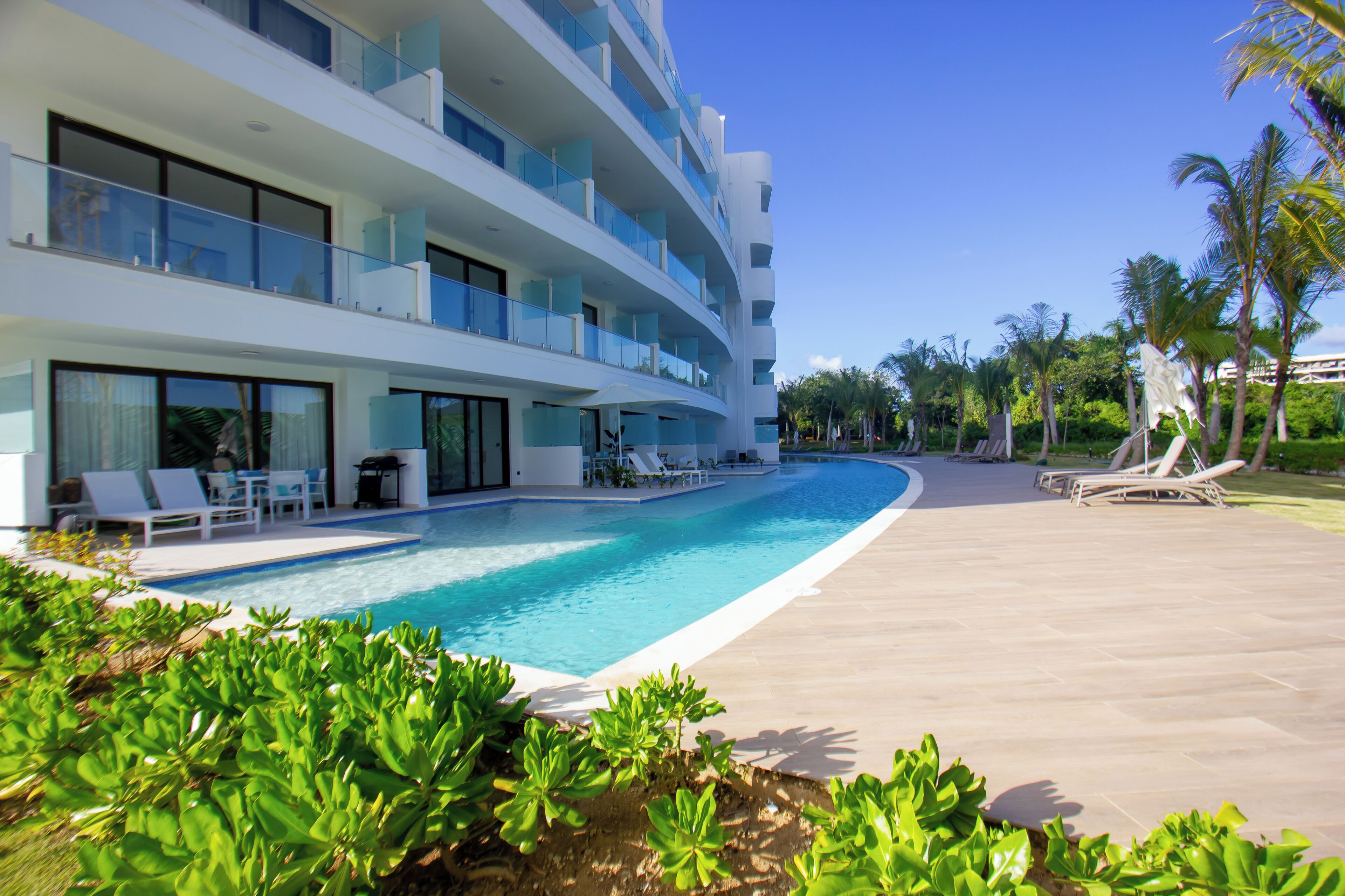 A modern hotel with a swimming pool, multiple balconies, and outdoor seating areas.