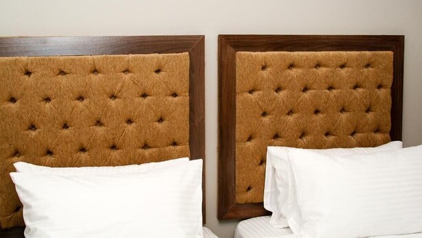 A hotel room with two beds, each with a tufted headboard and white bedding. - Sarum Lodge (Harare)