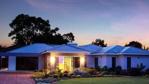 A modern house with a brick driveway, a well-maintained lawn, and a large tree in the background. - Sarum Lodge (Harare)