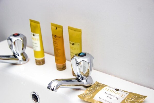 Un lavamanos con grifo de cromo, tres tubos amarillos de productos para el cabello y una etiqueta de producto capilar.