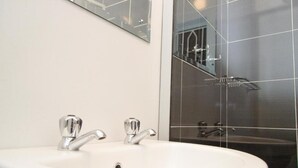 A bathroom with a white sink, two chrome faucets, and a mirror above the sink. - Sarum Lodge (Harare)