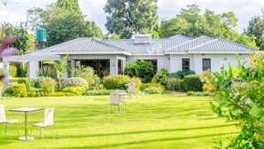 A two-story building with a covered patio area, a lawn, and outdoor seating. - Sarum Lodge (Harare)