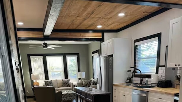 A modern kitchen with white cabinets, a wooden countertop, and a dining area with a table and chairs.