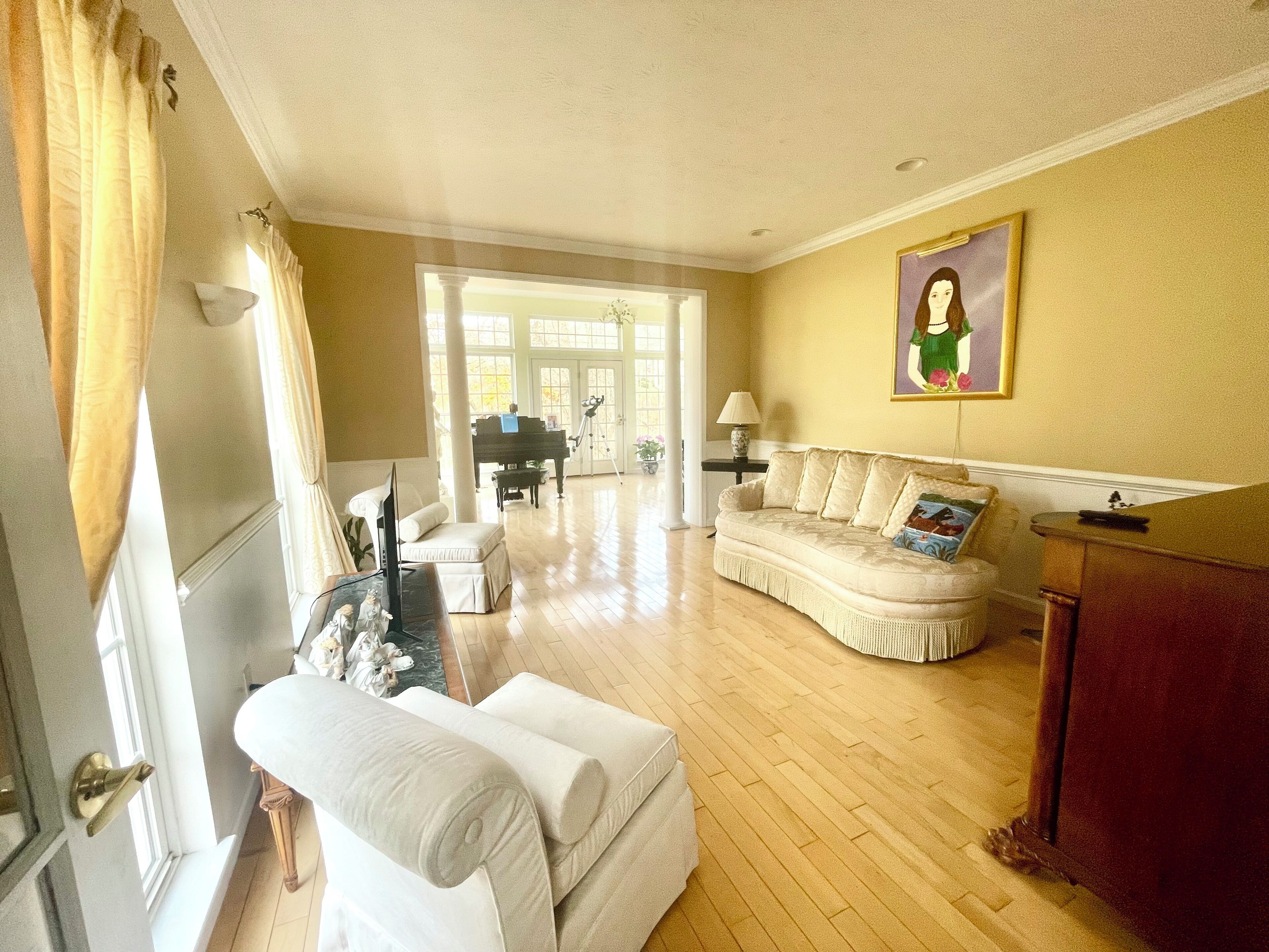 A spacious living room with a piano, a sofa, and a painting on the wall.