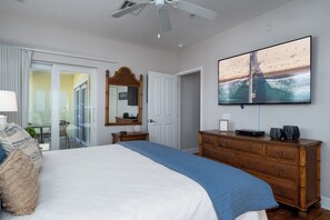 A bedroom with a bed, a dresser, a television, and a sliding glass door leading to a balcony. - Harbour House #301 "Harbour Retreat" (Fort Myers Beach)