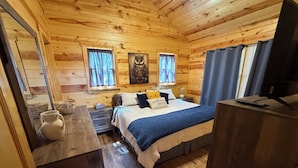A wooden cabin bedroom with a bed, bedside tables, a window with curtains, and a nightstand. - 
Charming 2 bed room mountain hideaway in Murphy (Murphy)
