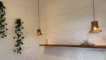 A room with white textured walls, a wooden shelf, and hanging pendant lights.