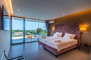 Ein Schlafzimmer mit einem großen Bett, Blick durch eine Schiebetür und einem Balkon.