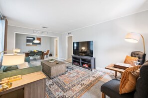 Ein modernes Wohnzimmer mit Fernseher, Sofa, Couchtisch und Teppich.