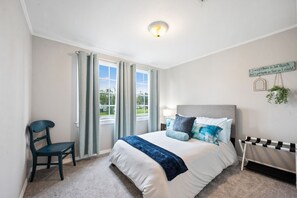 Ein Schlafzimmer mit Bett, Stuhl, Nachttisch, Wandschild und Heizkörper.