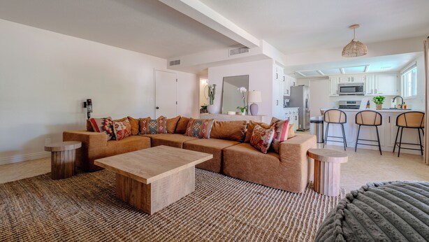 A modern living room with a sectional sofa, a wooden coffee table, and a patterned rug.