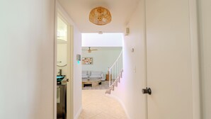 A hallway leading to a living area with a staircase, a ceiling fan, and a dining table.