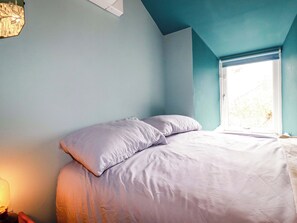 A bedroom with a bed, pillows, a window, and a light fixture. - Sunnybrae Cottage (Tintagel)