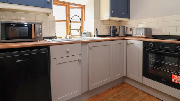 A kitchen with a microwave, coffee maker, toaster, and oven. - The Ranch (Prestatyn)