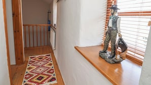 A staircase with a wooden handrail, a patterned rug, and a statue on a ledge. - The Ranch (Prestatyn)