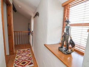 A staircase with a wooden handrail, a patterned rug, and a statue on a ledge. - The Ranch (Prestatyn)