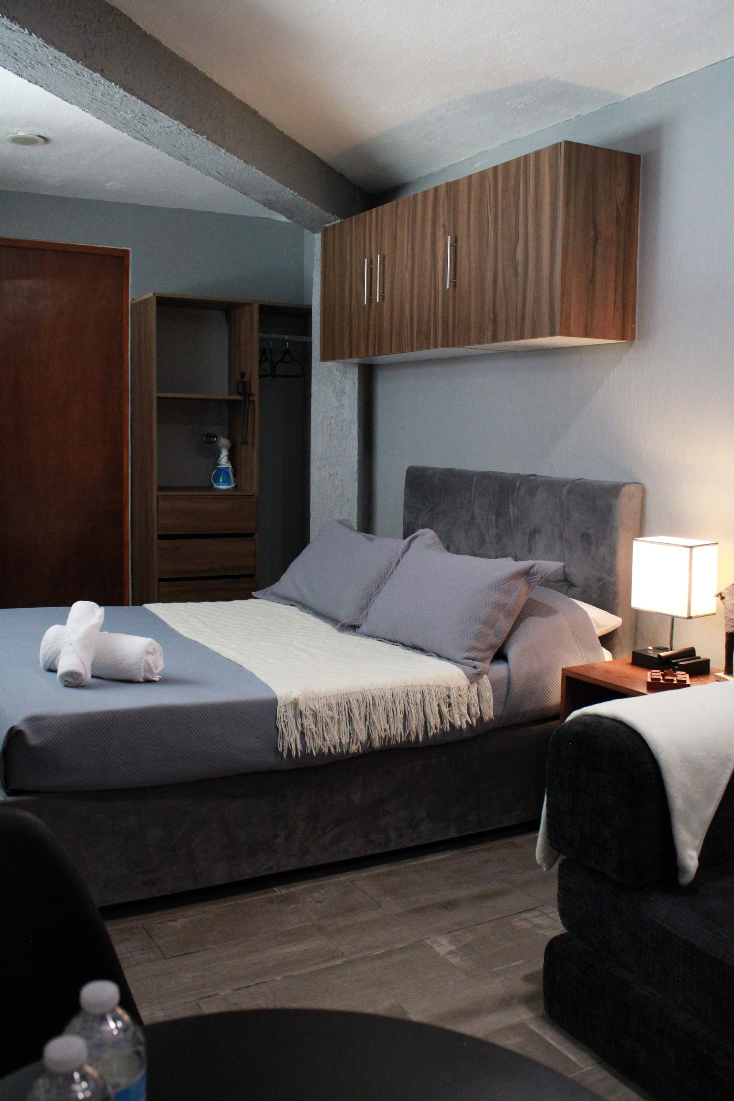 A hotel room with a bed, a wardrobe, a nightstand, and a chair.