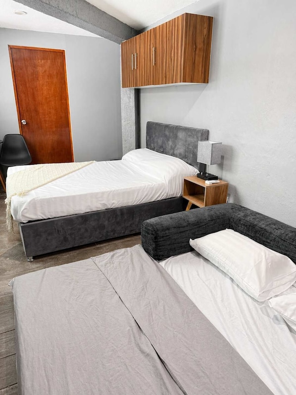 A bedroom with two beds, a wardrobe, a desk, and a chair.