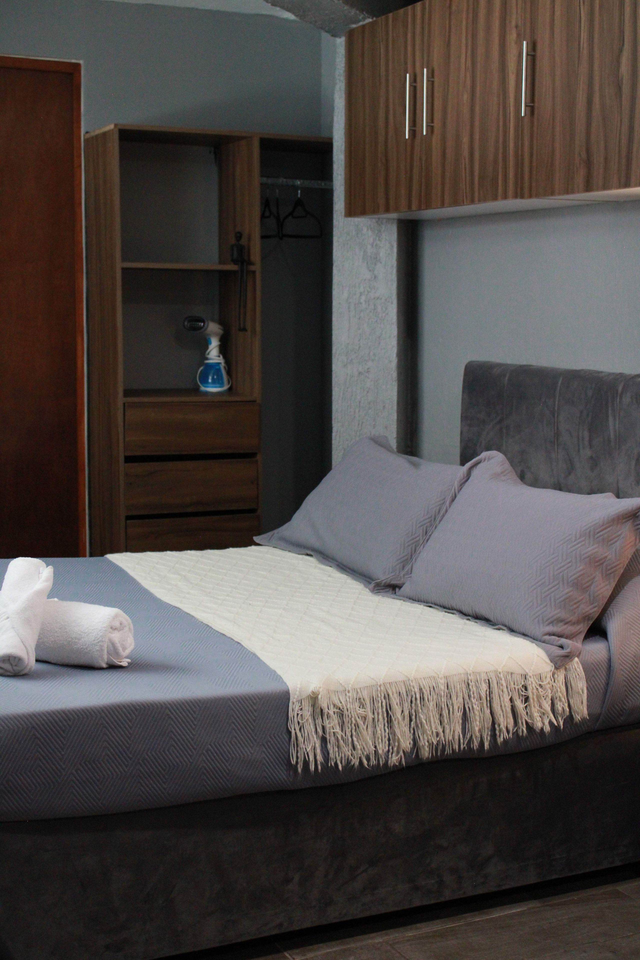 Une chambre à coucher avec un lit, une armoire et une table de chevet.
