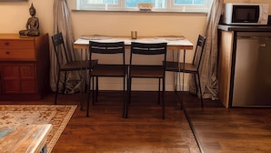 A room with a wooden desk, two chairs, a small statue, a microwave, and a refrigerator. - The Hideaway (Tintagel)