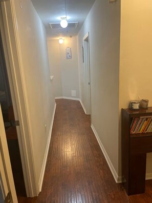 A hallway with wooden flooring, white walls, and a ceiling fan. - Lofty Grace Home 2 (Richmond)