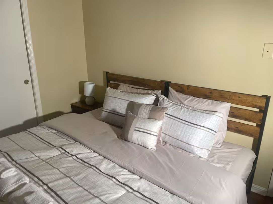 A bed with a wooden headboard, a beige blanket, and several pillows.