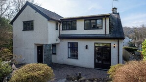 A two-story house with a stone foundation, a black roof, and a visible chimney. - Marina View (Windermere)
