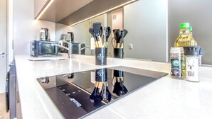 Une cuisine moderne équipée d’une plaque de cuisson à induction noire, d’un four à micro-ondes et d’une machine à café.