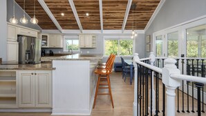 A kitchen with wooden ceiling beams, white cabinetry, and a bar area with a view. - Ocean Sound - 2nd Row - 4BR Folly Field Beach House - Heated Private Pool (Hilton Head Island)