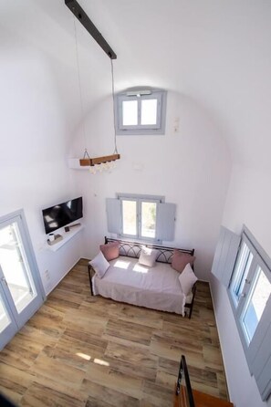A bedroom with a bed, a TV, a window, and a hanging light fixture. - DENIS Summer Living (Santorini)