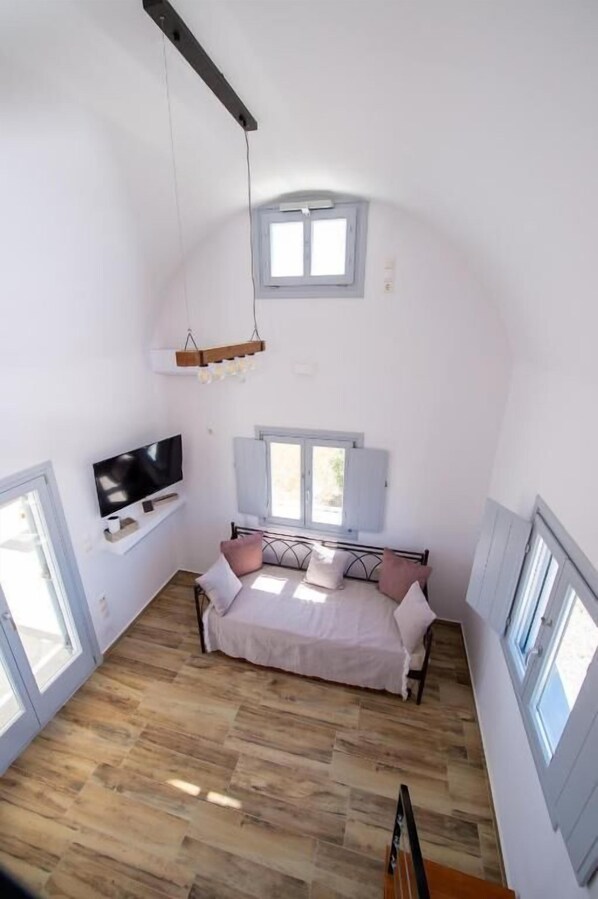 Un dormitorio con una cama, un televisor, una ventana y una lámpara colgante.