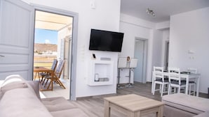 Una sala de estar moderna con un sofá, una mesa de centro, un televisor montado en la pared y un comedor con sillas y una mesa.