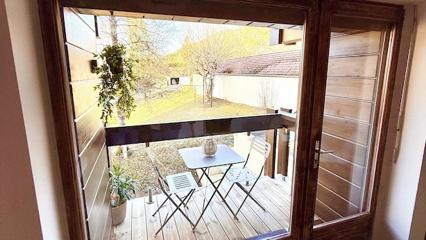 Una habitación con un amplio ventanal corredero que da a una terraza exterior con una mesa y sillas.